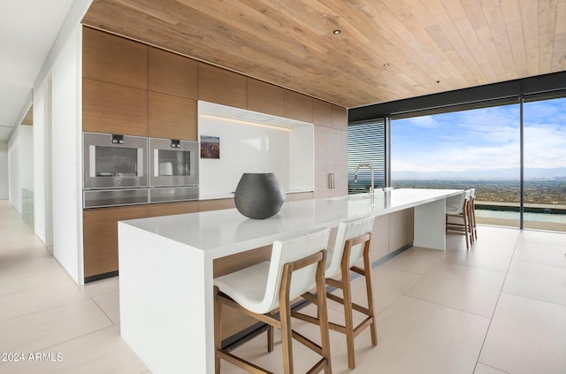 kitchen with light tile patterned floors, floor to ceiling windows, wood ceiling, modern cabinets, and brown cabinetry