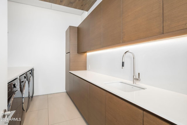 kitchen with light tile patterned floors, sink, and washing machine and clothes dryer