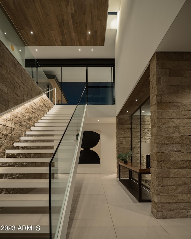 stairs featuring wood ceiling, a high ceiling, and tile patterned floors