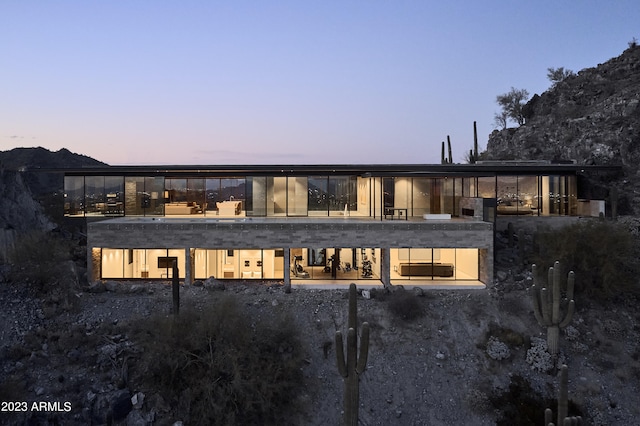 back house at dusk featuring a balcony