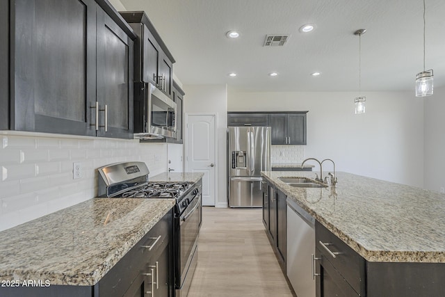 8518 S 8th Ln, Phoenix, AZ 85041 - kitchen featuring stainless steel appliances, a sink, light wood finished floors, recessed lighting, and tasteful backsplash