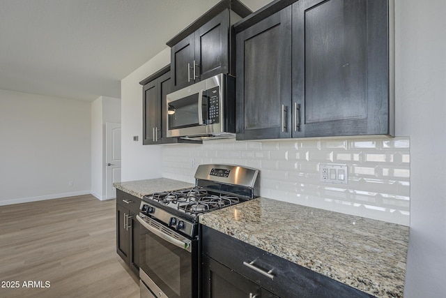 8518 S 8th Ln, Phoenix, AZ 85041 - kitchen with stainless steel appliances, decorative backsplash, light stone countertops, light wood-style flooring, and baseboards