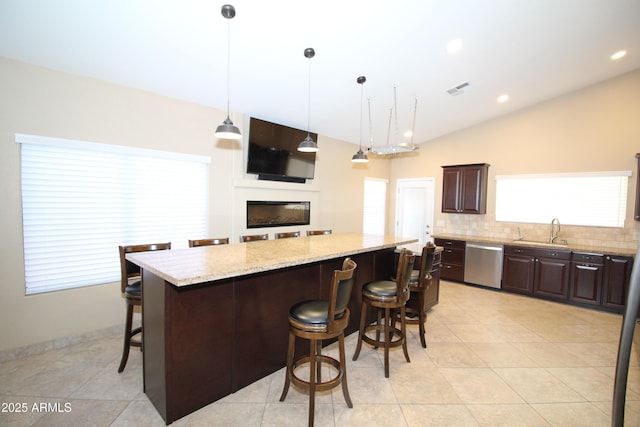 5437 W Bluefield Ave, Glendale, AZ 85308 - kitchen with stainless steel dishwasher, a center island, a breakfast bar, dark brown cabinetry, and backsplash