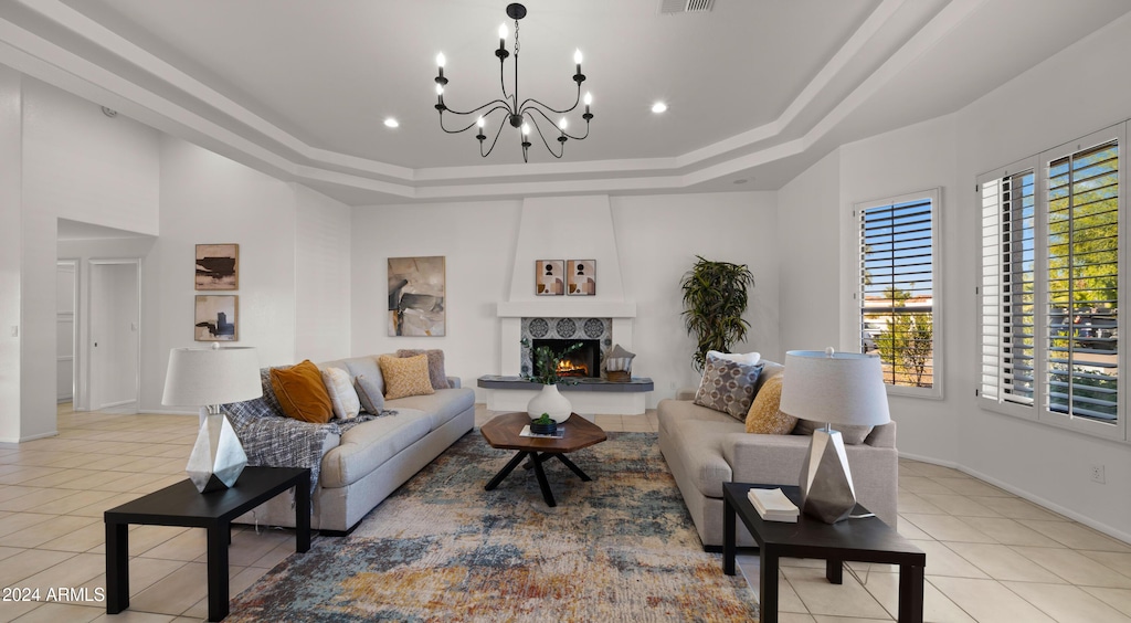 living room with an inviting chandelier, light tile patterned floors, and a tray ceiling