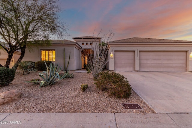 view of front facade featuring a garage, driveway, and stucco siding