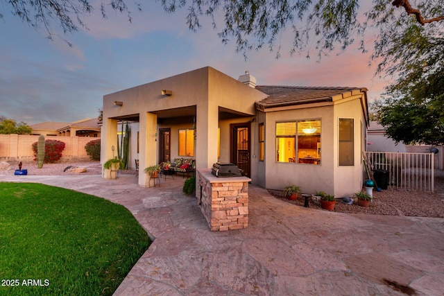 view of front of property featuring a patio, a chimney, fence, a yard, and stucco siding