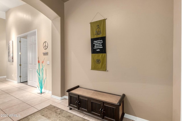 hall featuring baseboards and light tile patterned flooring