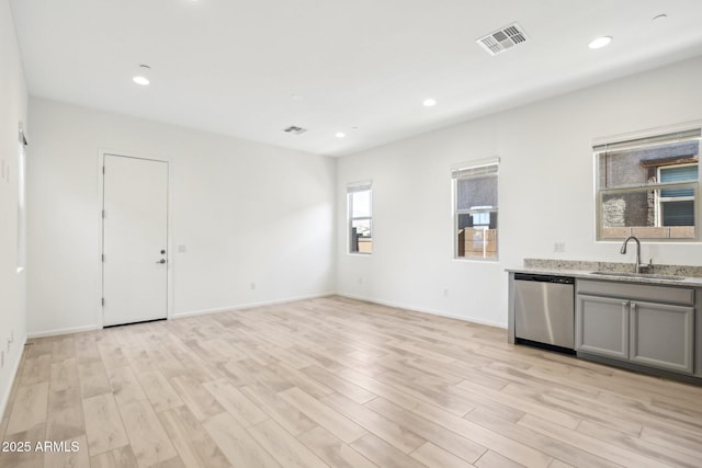 interior space featuring sink, light hardwood / wood-style flooring, gray cabinetry, light stone counters, and stainless steel dishwasher