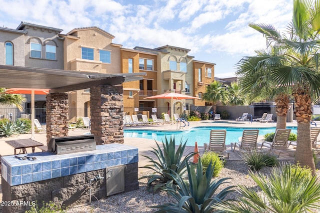 view of swimming pool with a grill, an outdoor kitchen, and a patio