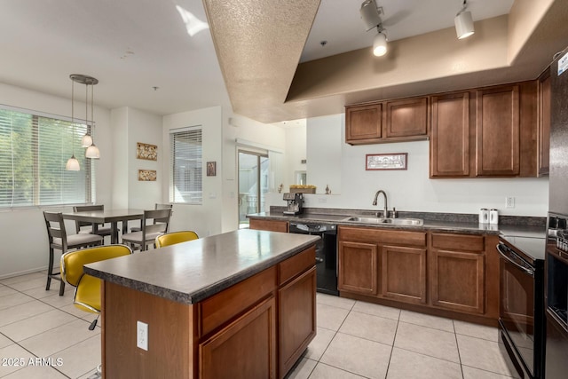 kitchen with a kitchen island, black appliances, sink, hanging light fixtures, and rail lighting