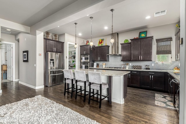 kitchen featuring a breakfast bar area, visible vents, dark wood finished floors, stainless steel appliances, and dark brown cabinets