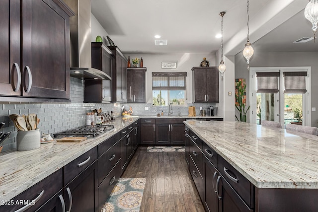 kitchen featuring tasteful backsplash, wall chimney exhaust hood, dark wood-type flooring, and a sink