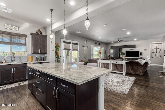 kitchen with a sink, visible vents, backsplash, and dark wood-style flooring