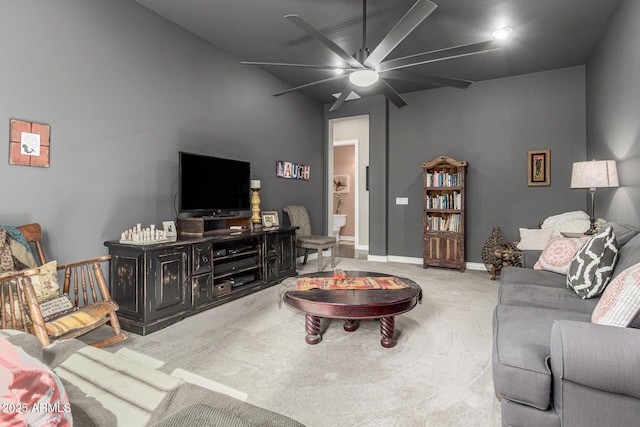 carpeted living area with baseboards and a ceiling fan