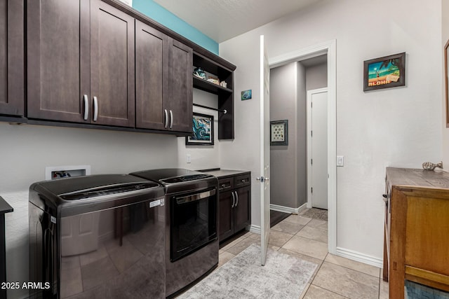 washroom featuring washing machine and dryer, light tile patterned floors, cabinet space, and baseboards
