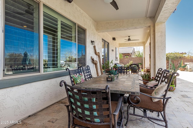 view of patio with outdoor dining area, a ceiling fan, and fence