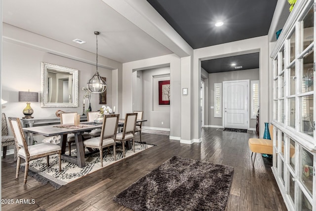 dining space with dark wood finished floors, a notable chandelier, baseboards, and visible vents