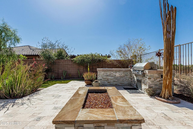 view of patio with area for grilling, a fenced backyard, and an outdoor kitchen