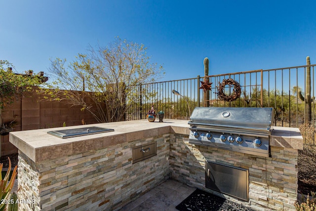 view of patio with area for grilling, fence, and an outdoor kitchen