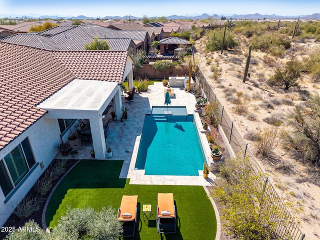 view of swimming pool with a yard, a mountain view, a patio, and a fenced backyard