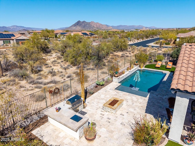 view of swimming pool featuring a mountain view, a fenced backyard, an outdoor kitchen, and a patio area