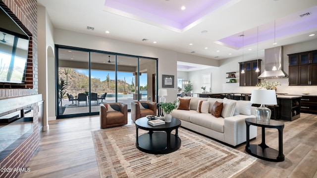 living room with light hardwood / wood-style floors and a tray ceiling