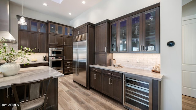 kitchen with wine cooler, light stone counters, pendant lighting, and stainless steel appliances