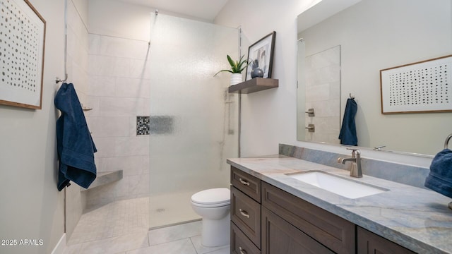 bathroom featuring vanity, tile patterned floors, toilet, and tiled shower