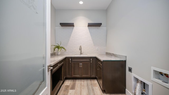 kitchen with dark brown cabinetry, sink, backsplash, and light hardwood / wood-style flooring