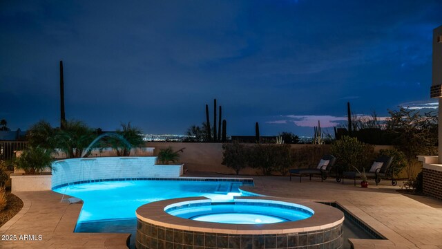 pool at dusk with a patio area and an in ground hot tub