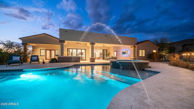 pool at dusk featuring an in ground hot tub, ceiling fan, a patio area, and pool water feature