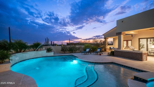 pool at dusk featuring pool water feature and a patio area