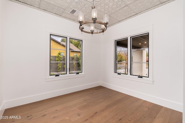 unfurnished room featuring hardwood / wood-style flooring and a chandelier