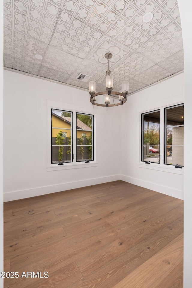 unfurnished room with a wealth of natural light, wood-type flooring, and a chandelier