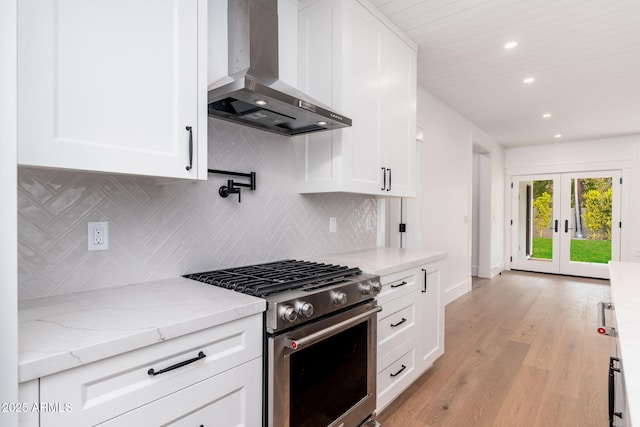 kitchen with white cabinetry, wall chimney range hood, and stainless steel gas range