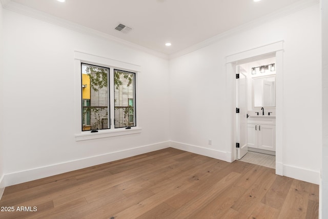 empty room with ornamental molding, sink, and light hardwood / wood-style flooring