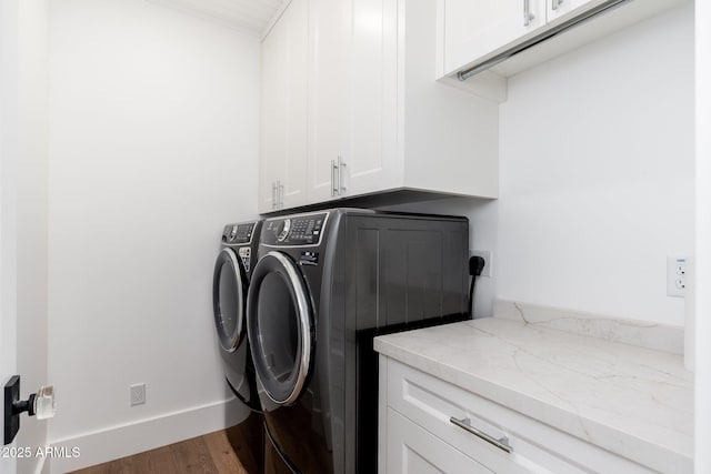 laundry room featuring dark wood-type flooring, washer and clothes dryer, and cabinets