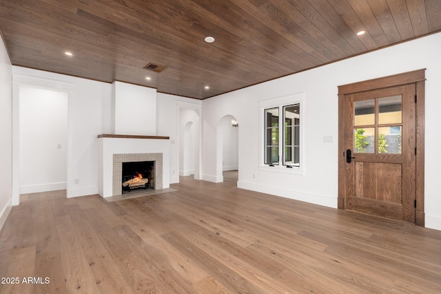 unfurnished living room with hardwood / wood-style flooring, ornamental molding, a fireplace, and wood ceiling