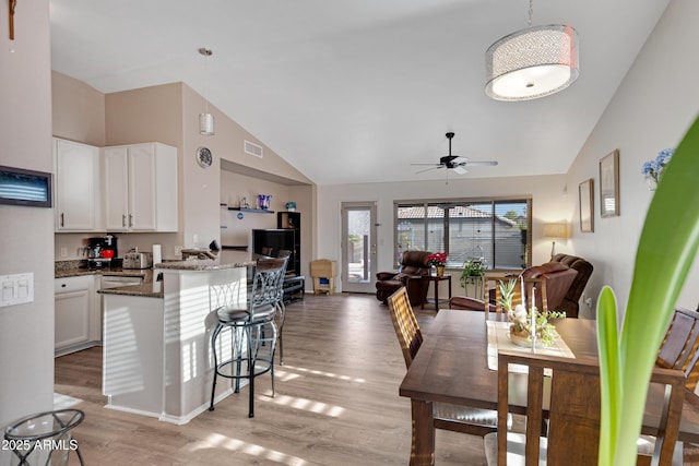 dining space with ceiling fan, vaulted ceiling, and light hardwood / wood-style floors