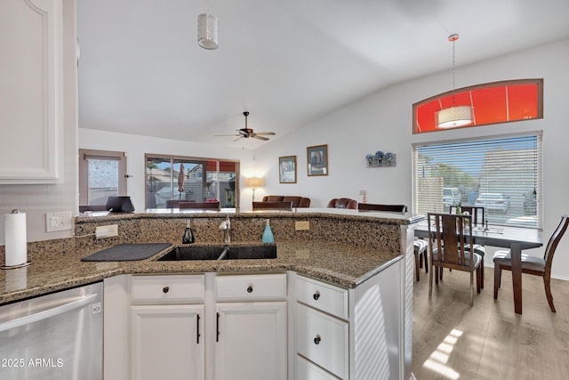 kitchen featuring lofted ceiling, sink, decorative light fixtures, stainless steel dishwasher, and white cabinets