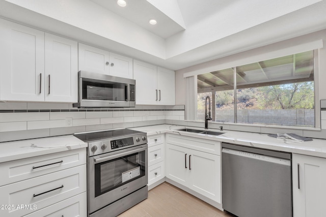 kitchen with appliances with stainless steel finishes, white cabinetry, and sink