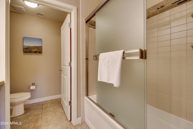 bathroom with toilet, combined bath / shower with glass door, visible vents, tile patterned flooring, and baseboards
