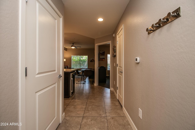 hallway with a textured wall, baseboards, light tile patterned flooring, and recessed lighting