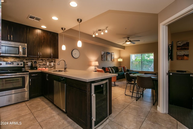 kitchen featuring beverage cooler, visible vents, a sink, a peninsula, and stainless steel appliances