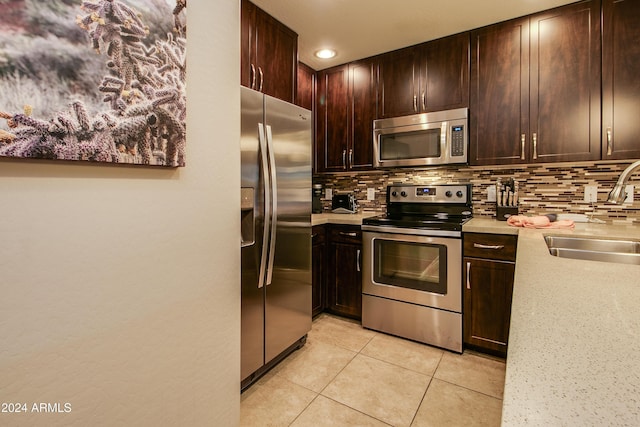kitchen featuring a sink, stainless steel appliances, backsplash, and light tile patterned floors