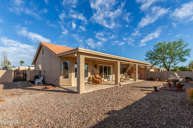 back of house featuring stucco siding, a fenced backyard, a tile roof, and a patio