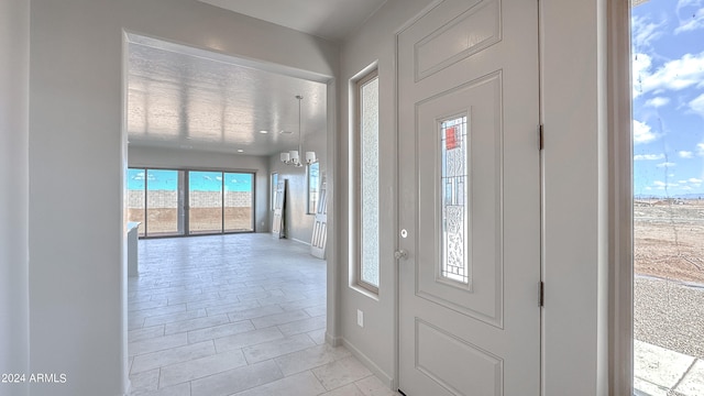 foyer entrance featuring a healthy amount of sunlight, light tile patterned floors, and a chandelier