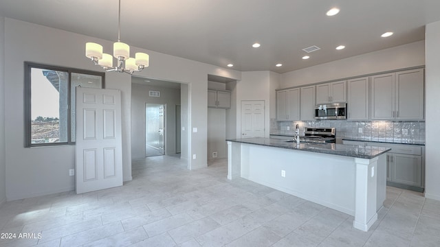 kitchen featuring light tile patterned floors, appliances with stainless steel finishes, dark stone countertops, and gray cabinetry