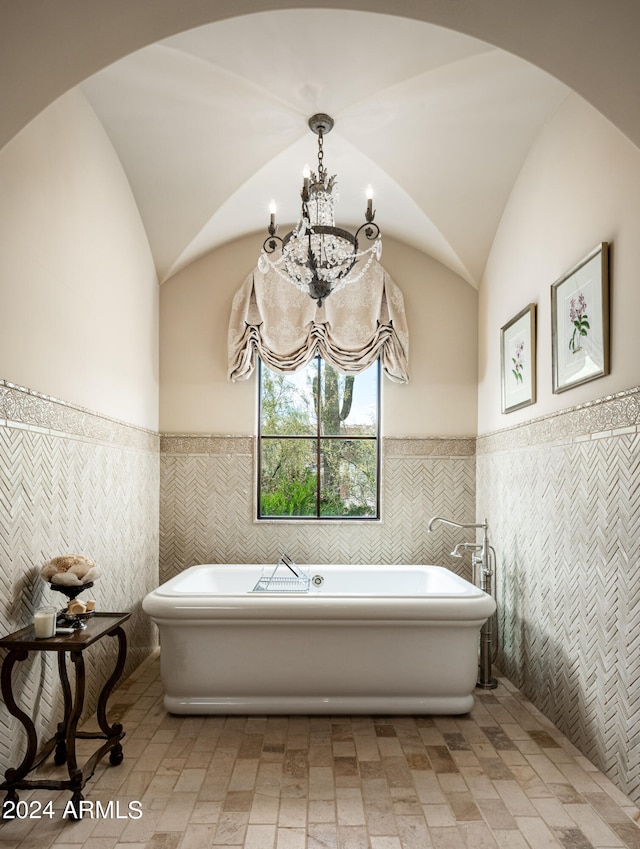 bathroom featuring lofted ceiling, a tub, tile walls, and a chandelier