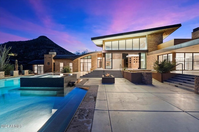 back house at dusk with a patio and a swimming pool with hot tub